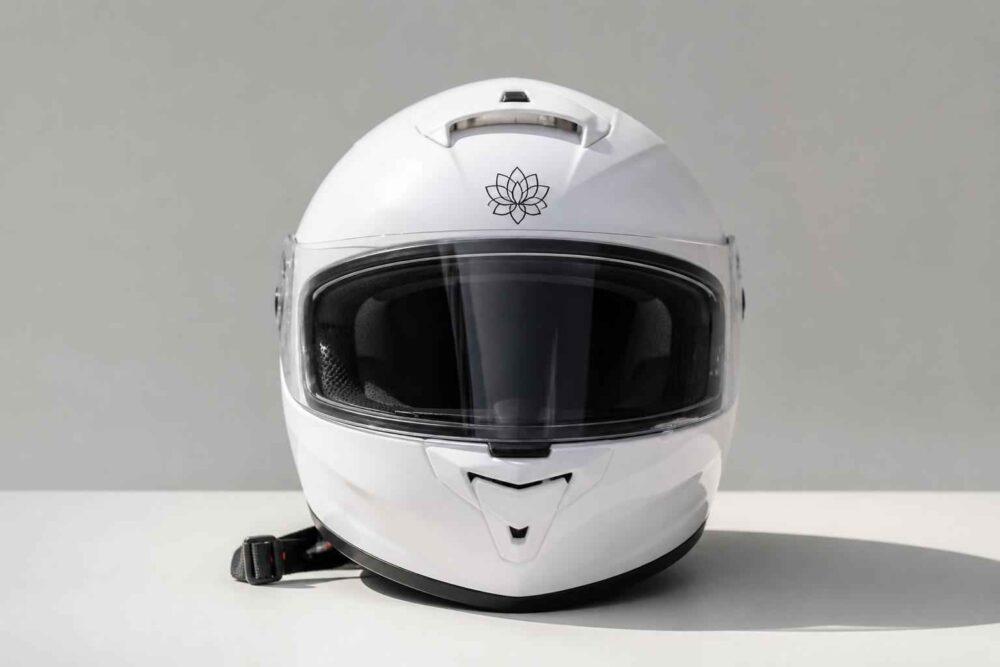Biały kask motocyklowy z ciemną szybą i zapięciem na jasnym tle