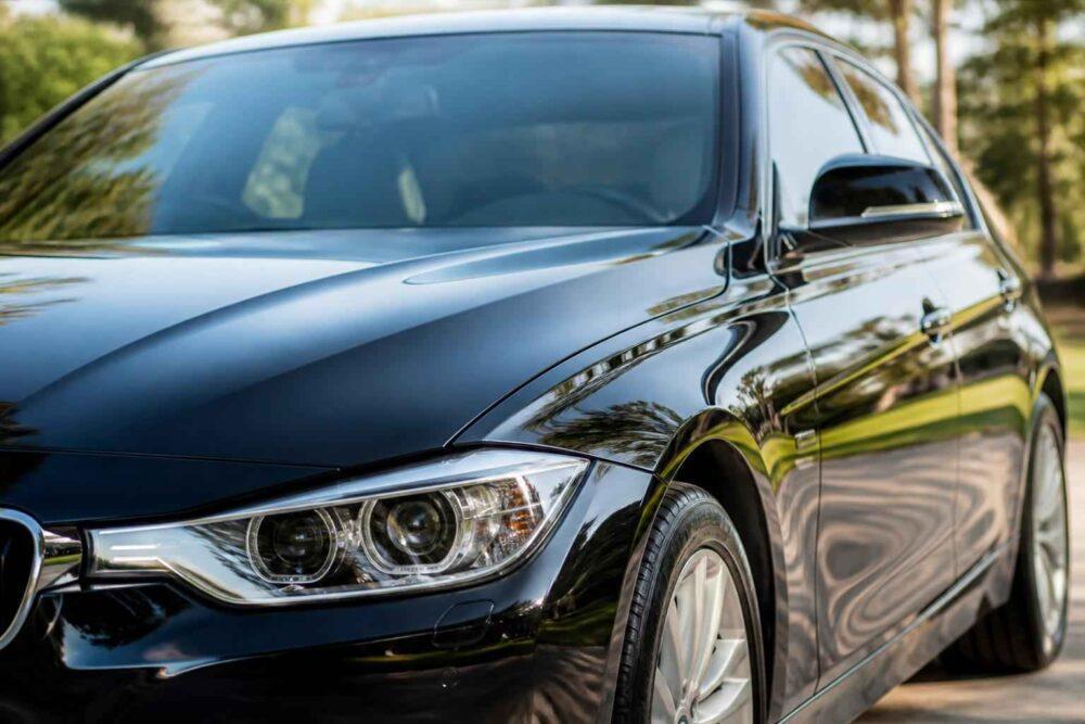 Błyszczące czarne BMW zaparkowane przy ulicy, widok z przodu i boku samochodu