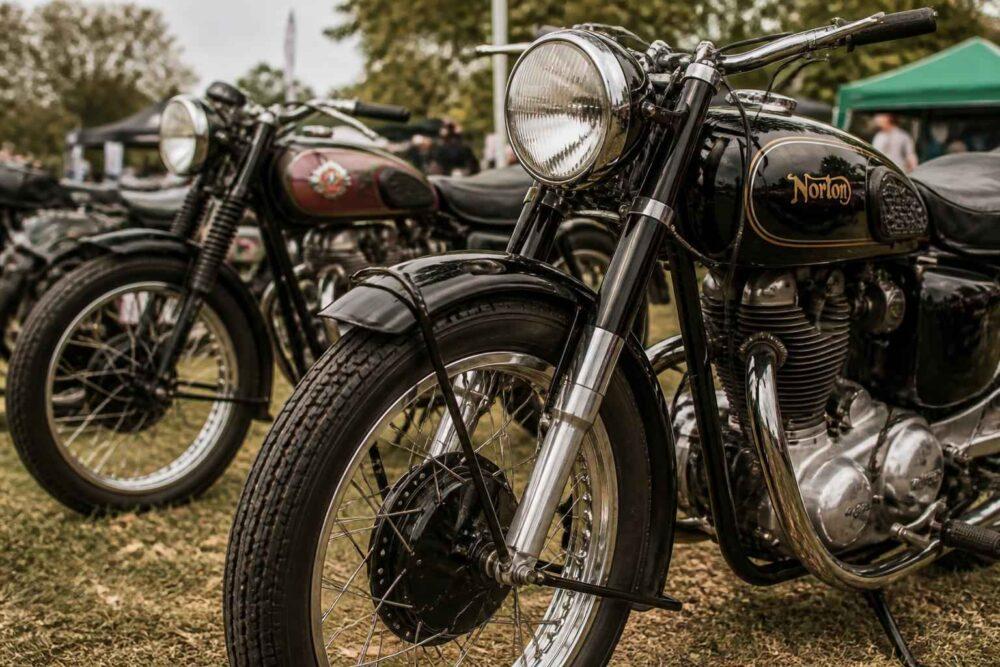 Dwa klasyczne motocykle zaparkowane na trawie podczas plenerowego zlotu motocyklowego