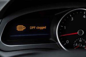 Deska rozdzielcza samochodu z komunikatem DPF clogged i ikoną filtra cząstek stałych