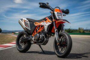 Pomarańczowy motocykl KTM zaparkowany na asfaltowym torze wyścigowym pod błękitnym niebem